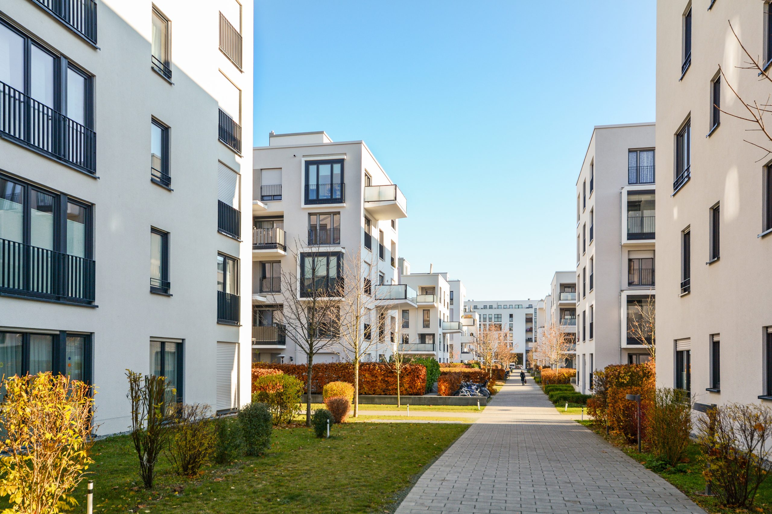White apartment buildings with a sidewalk separating them